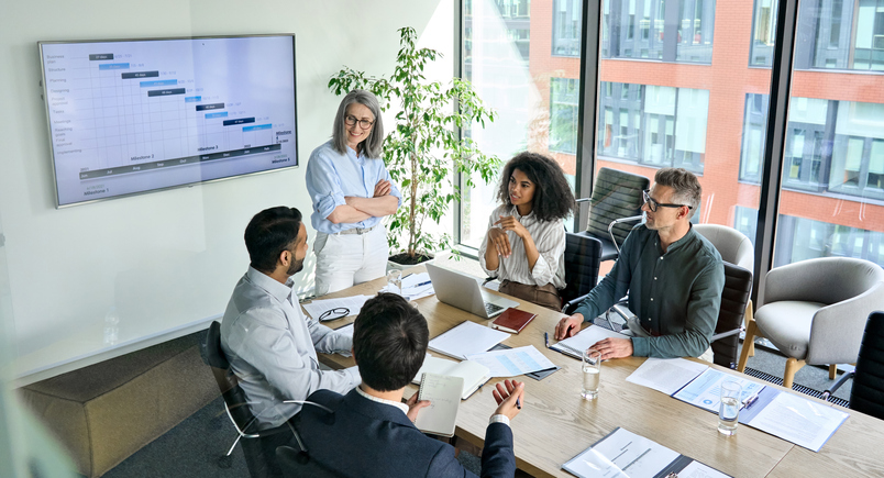 Woman standing in front of a table of employees